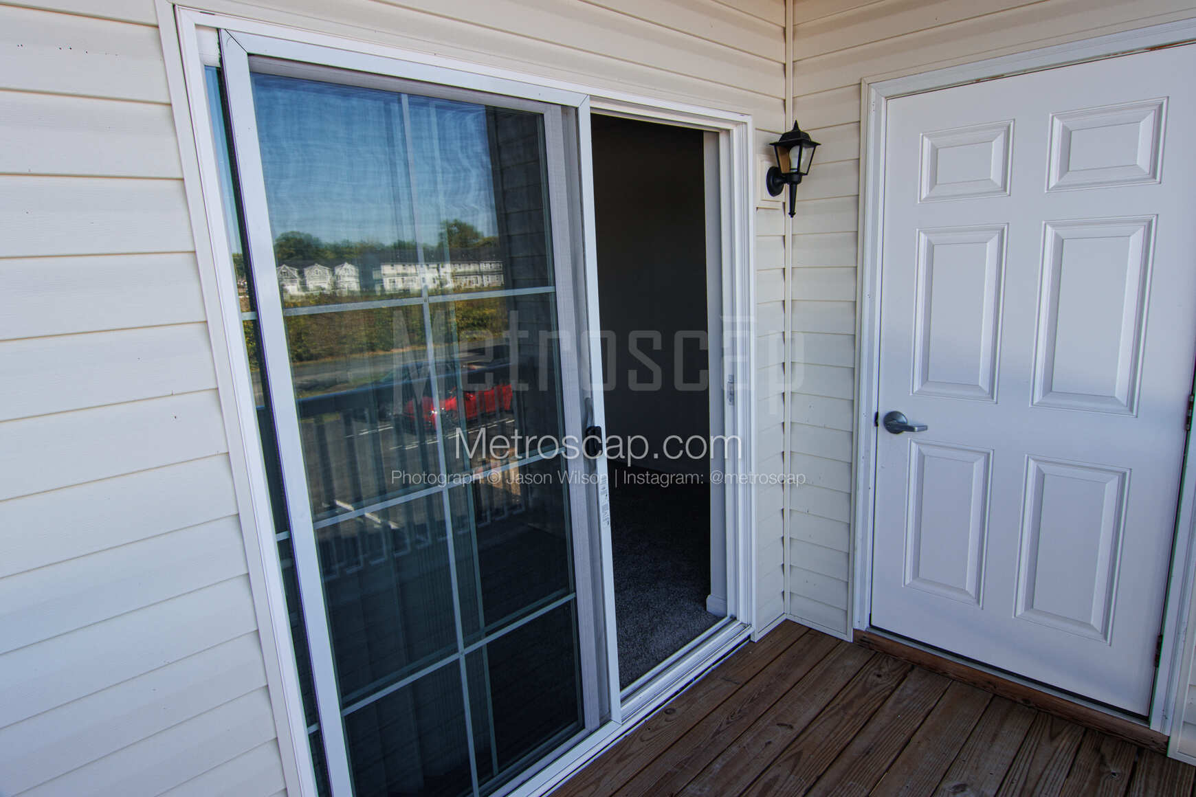 A private patio or covered balcony with a sliding glass door and a wooden deck.