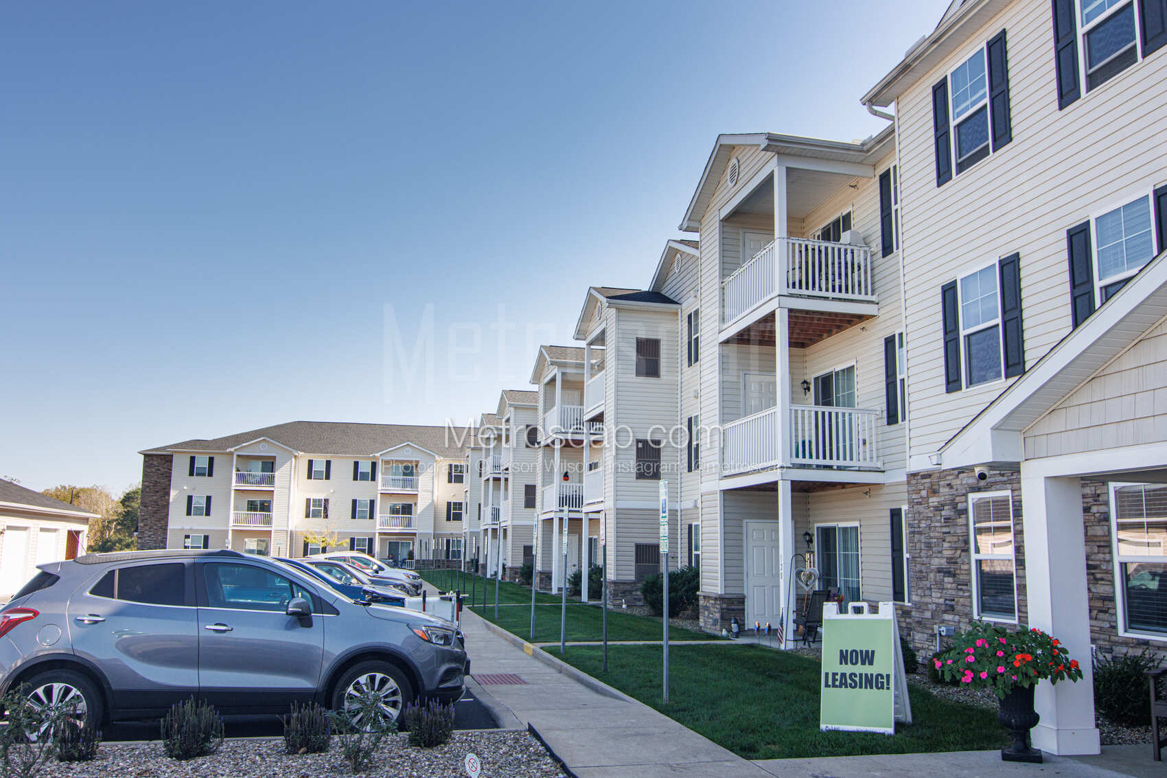 The exterior of a modern apartment building with balconies and a "Now Leasing" sign